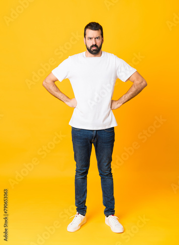 Full-length shot of man with beard over isolated yellow background angry