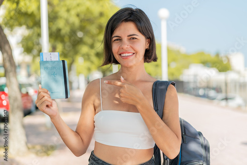 Young pretty Bulgarian woman holding a passport at outdoors and pointing it
