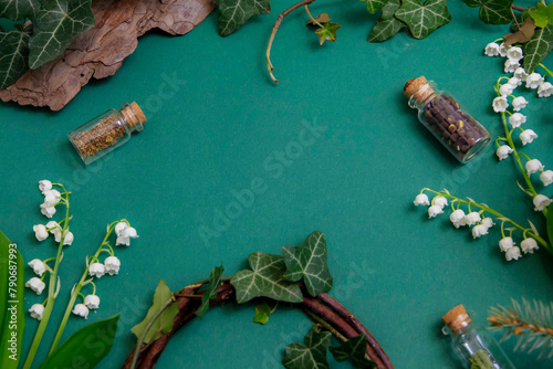 Kompozycja na stole na zielonym tle w otoczeniu roślinności: bluszcz, konwalie. 