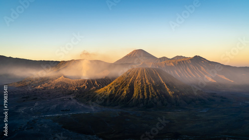 Volcano spewing smoke into sky among natural mountain landscape