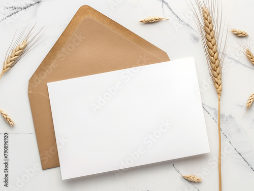 Mise en scène simple d'un carton d'invitation vierge blanc sur fond blanc-gris, mockup élégant décoré par des brins de blé pour une touche estivale