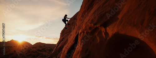 solitary climber ascends the rugged face of a steep cliff, reaching towards the peak as the sun sets in the background, panoramic banner of climbing sport