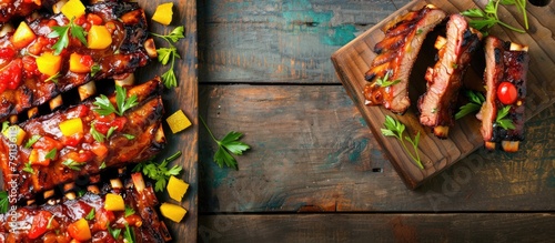 Barbecue pork spare ribs topped with fruit relish displayed from above on a vintage wooden board, with space for text.