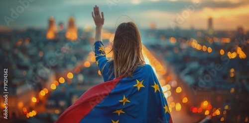 A woman wearing a European flag cloak stands on the roof of Europe's leading city, overlooking and waving at it with her back to the camera. In front is a blurred background of European landmarks.