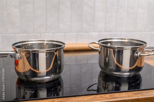 Dwa stalowe garnki stoją na kuchence w domowej kuchni 