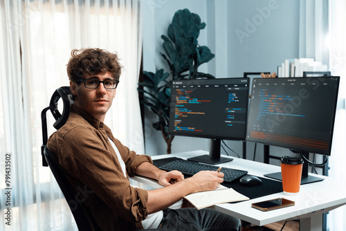 IT developer in online software development information looking at camera surrounded coding pc screens at side view, working on design new program for latest version at modern home office. Gusher.