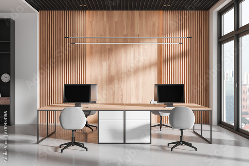 Modern workspace interior with pc monitors on tables, panoramic window