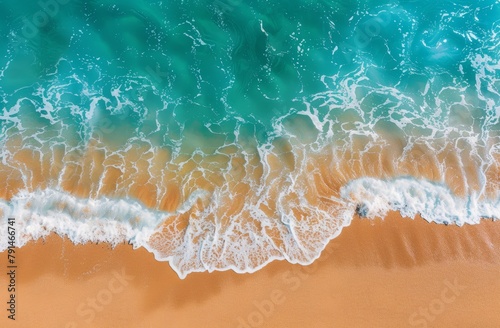A top view of the beach with waves gently lapping at the golden sand