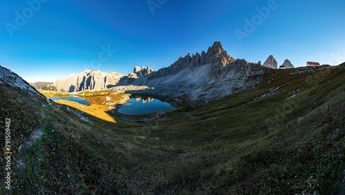 Panoramic photo of the Monte Paterno (Paternkofel) over the lake Laghi dei Piani with a reflection in the clear calm water surface and the Tre Cime di Lavaredo in the background