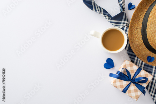 Father's Favorites: Overhead view of a straw hat, dapper necktie, gift box, cup of fresh coffee, and heart cutouts on white. Great for Father's Day wishes or advertisements