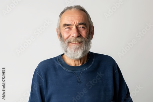 Smiling old man with beard and gray hair in blue sweatshirt stands alone looks at camera headshot