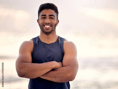 Portrait, arms crossed and man for beach fitness, muscle and strong with biceps, health and wellness outdoor. Athlete, sport and training in nature with confidence, endurance and workout by the ocean