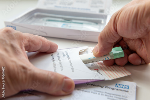 London. UK- 04.17.2024. A person putting the collected bowel cancer sample in the envelope to be sent off for testing.