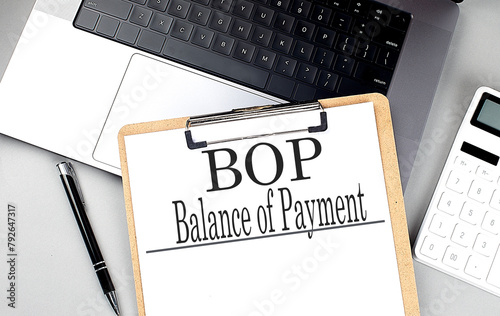 BOP- BALANCE OF PAYMENT word on clipboard on laptop with calculator and pen