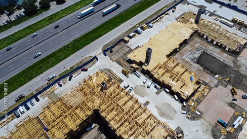 Interstate 35 highway and large apartment complex under construction, Dallas, Texas, Slab foundation, precast concrete elevator shafts, wooden framework of multi-story rental community, aerial