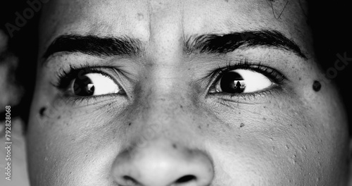 One paranoid worried young black woman macro close-up eyes looking sideways with intense preoccupation and obsession in dramatic black and white monochrome