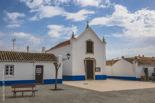 City of Porto Covo with traditional Alentejo houses painted white with blue strip and red windows. Streets of the picturesque village of Porto Covo, located in the vicentine coast, Portugal.