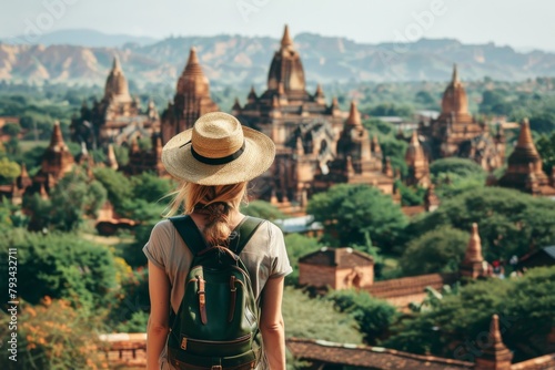 A female tourist with a straw hat stands admiring the ancient Bagan temples and pagodas in Myanmar