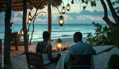 Black African couple on the beach, on vacation holiday, dining on the beach sand, in a intimate romantic date night valentines moment, bespoke rustic restaurant with hanging lights in the evening