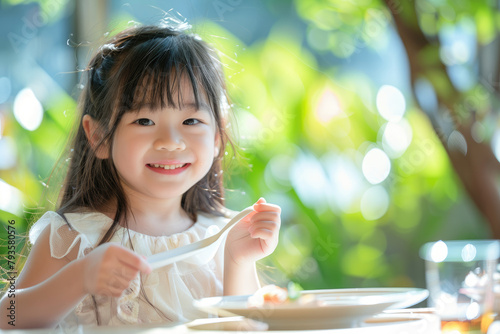 a happy young Asian girl eating at a table in a children's restaurant, holding a spoon and plate, with long hair bangs, focusing on her face, in natural light