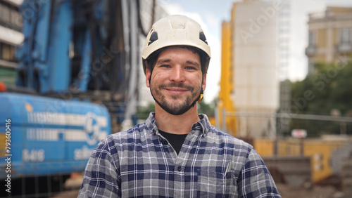 Confident construction site worker portrait. Smile constructor man look at camera. Builder engineer wear white helmet. Real estate agent plaid shirt. Guy build new house city street Erector person job