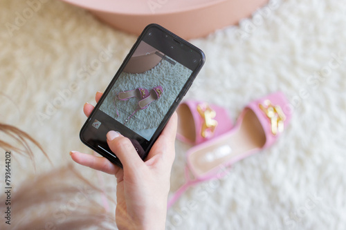 Woman taking photo of pink high heels shoes on beige rug with smartphone. Female blogger, influencer or stylist hand