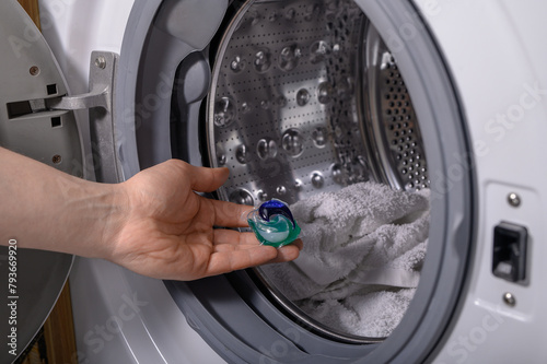 Kapsułka do prania z detergentami wkładana do pralki z brudnymi ubraniami 