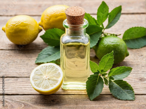 A small transparent glass bottle of melissa oil on a wooden table fresh green melissa leaves and lemon fruit ecofriendly medicinal solution natural background sunny day