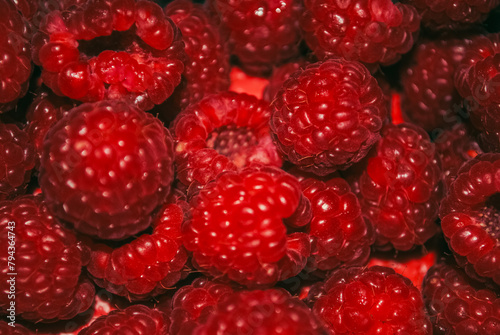 Macro shot of fresh raspberries on a red background.