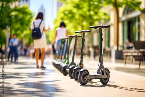 A lineup of app-controlled rental scooters on a busy city walkway, blurred pedestrians in the background. Concept of seamless urban commuting with app-based rental services