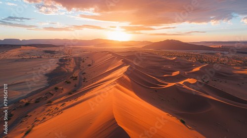 Colorful sunset over majestic sand dunes, vast desert aerial landscape with mountains in the background