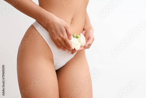 Beautiful young woman in panties with carnation flowers on white background, closeup