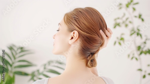 Rear view of a Japanese woman tying up her hair in a white room.
