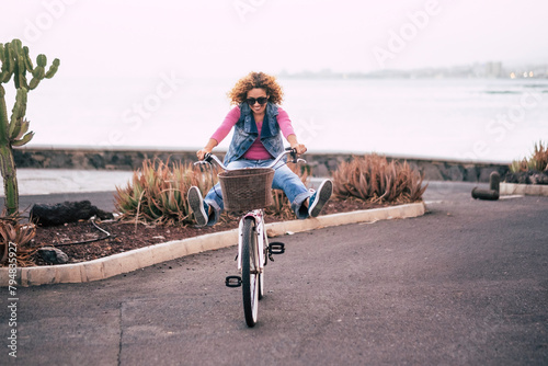 One young lady riding bike alone on the street with ocean coastline view. Outdoor leisure activity green transport woman. People and healthy lifestyle. Concept of tourist on vacation having fun