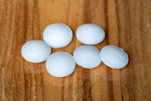 Naphthalene mothballs isolated on wooden background. It is also known as moth flakes, naphthalin, antimite, and hexalene.