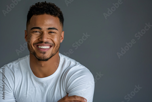 Smiling, handsome young man with arms crossed. Joyful, cheerful male laughing with hands folded in a studio setting