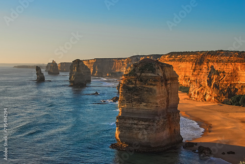 Beautiful view of limestone cliffs and rock formations cast in the golden hue of sunset along the southern coast of Victoria, Australia.