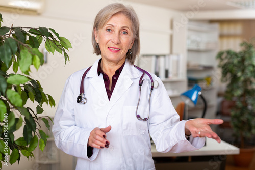 Portrait of polite elderly female health worker meeting patient in medical office