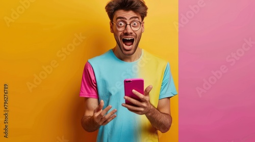 The shocked expression of a man looking at a smartphone screen, wearing a cheerful bright yellow shirt.