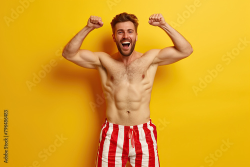 Photo guy fist up scream yes swimmer ocean distance win wear red striped set shorts isolated on yellow color background