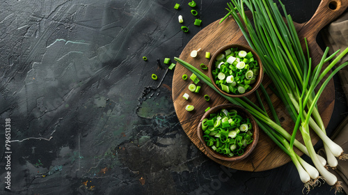 Wooden board and bowl with fresh green onion on dark background