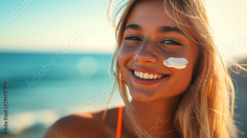 Lächelnde blonde Frau mit Sonnencreme auf der Wange am Strand
