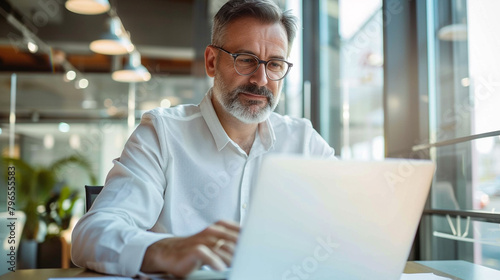 Mature business man executive manager looking at laptop computer watching online webinar training or having virtual meeting video conference taking notes