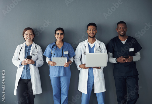 Doctor, teamwork and technology on wall background for research, planning and multimedia workflow. Healthcare worker, group and nurse in portrait with laptop, tablet and phone for contact or about us