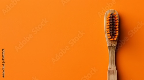  Close-up of a wooden toothbrush against an orange backdrop A smaller toothbrush is positioned in the brush's bristles