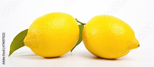 Two lemons with leaves on white surface
