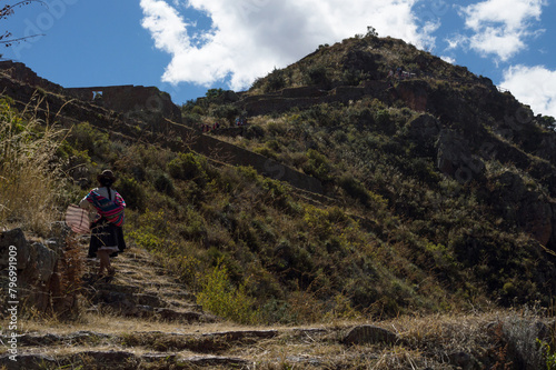 Peruvian woman climbing stairs on the trail leading to the ancient city of Pisac on top of the mountain