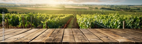 Wooden table overlooking a lush vineyard landscape with sunlight in the background