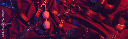 set of BDSM sex toys with handcuffs, whip flogger, butt anal plug for submission and domination on a red background. Wide header cover for a horizontal banner for sex shop