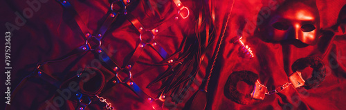 set of BDSM sex toys with handcuffs, whip flogger, butt anal plug for submission and domination on a red background. Wide header cover for banner for sex shop